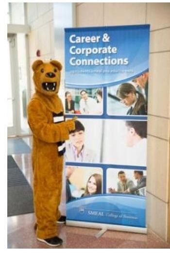 Photograph of the Nittany Lion mascot in a full bear costume standing beside a tall pull-up banner. The banner reads "Career & Corporate Connections" above four small photos of students and recruiters talking, with the Smeal College of Business shield logo at the bottom.